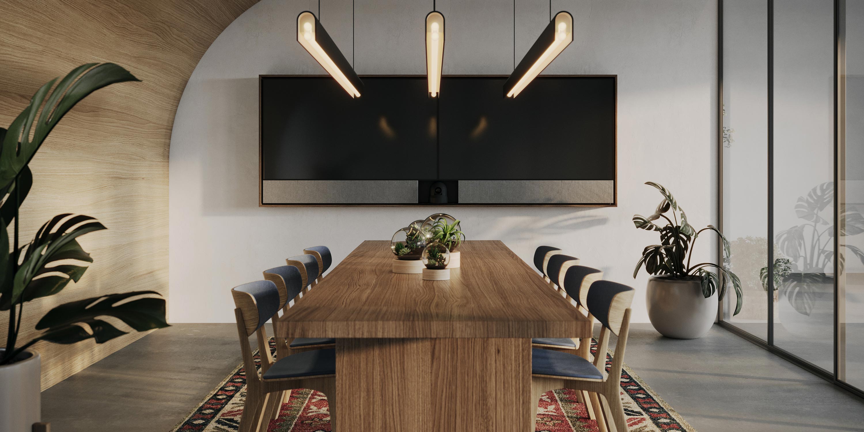 Modern conference room with a wooden table, large screen, and hanging pendant lights.