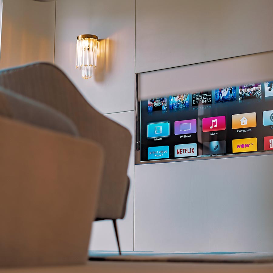 Close-up of a hidden television panel displaying various streaming options in a minimalist modern setting.