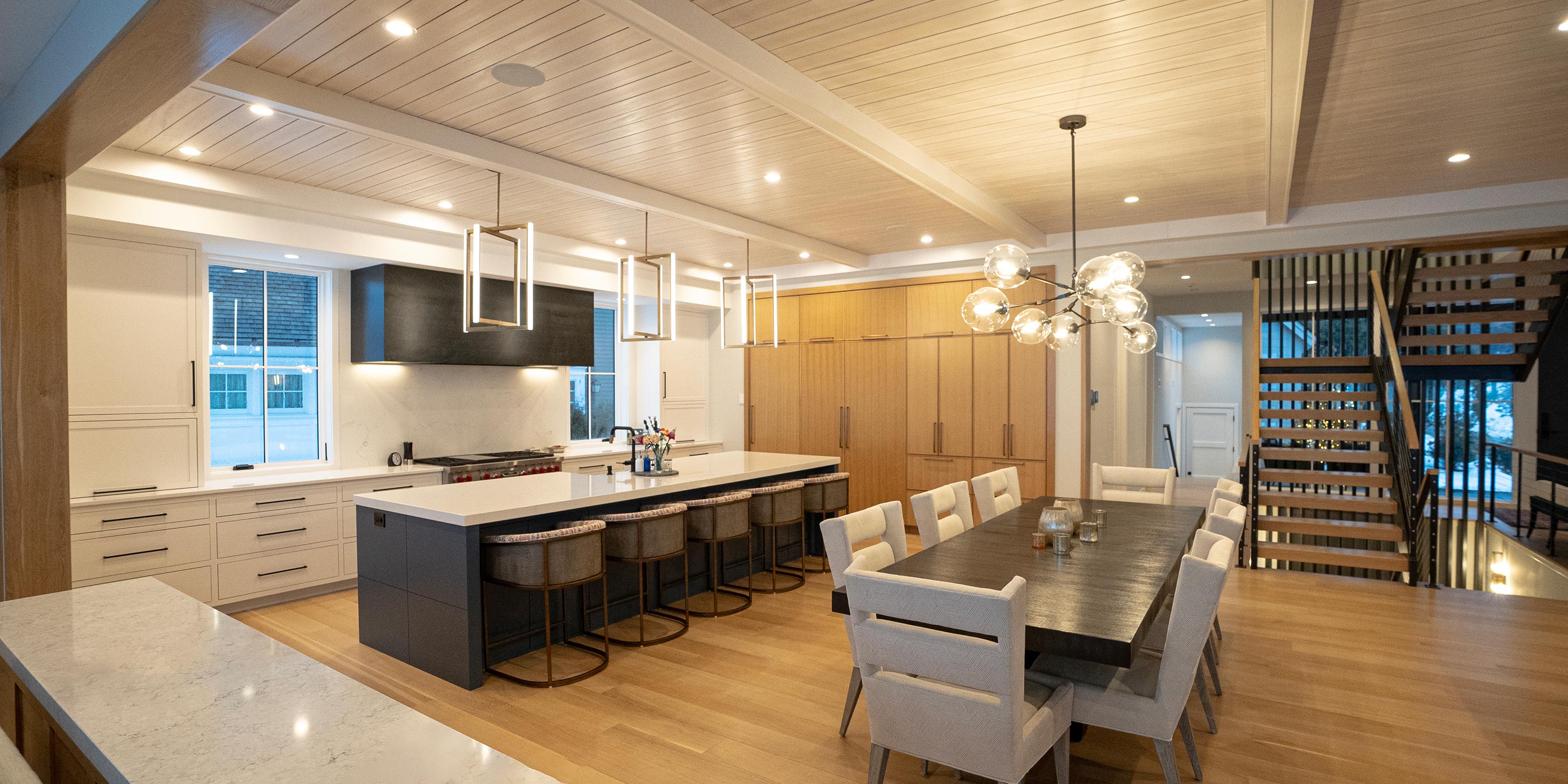 Expansive kitchen with a large island, modern lighting, and a dining area with stylish seating.