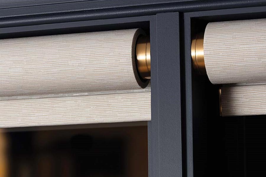 Close-up of two elegant, textured fabric roller shades with a brushed metal finish, highlighting precision craftsmanship.