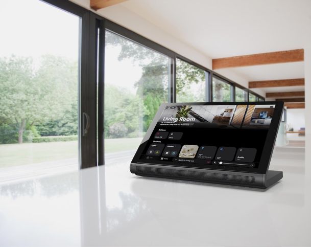 Smart home control tablet on a white counter in a bright, modern space.