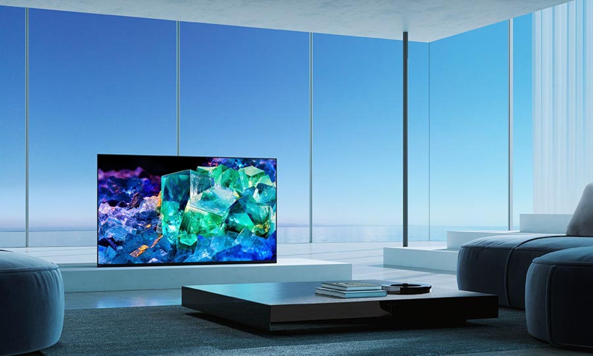 Modern, open space with a vibrant TV display showing colorful crystals, set against a blue sky.