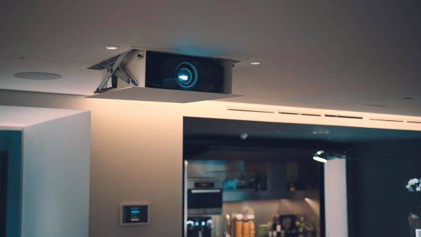 Retractable ceiling projector in a modern home theater setting.