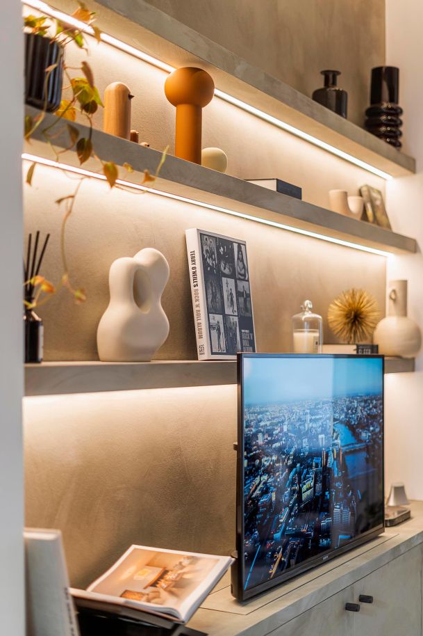 Decorative shelving with warm LED backlighting and a mounted television.