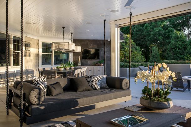 Stylish covered patio with a hanging daybed, dining area, and outdoor TV.
