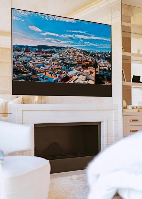 A fireplace with a sleek mounted TV above, showcasing a vibrant city view on the screen.