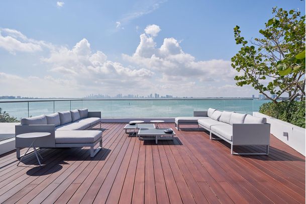 Modern outdoor terrace with ocean views, glass railing, and sleek seating.