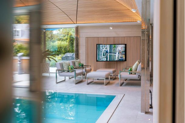 Luxurious indoor pool area with a mounted TV and stylish seating.