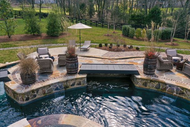 Outdoor patio with a pool, stone walkway, and lounge seating.