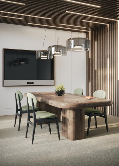 A modern conference room with a wooden table, green chairs, and hanging glass pendant lights.