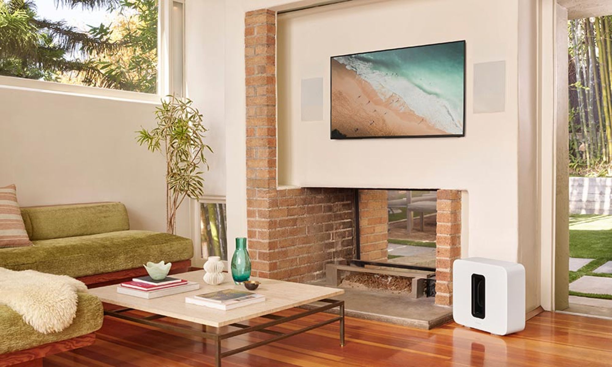 Living room with a wall-mounted TV above a fireplace and a white subwoofer on the floor.